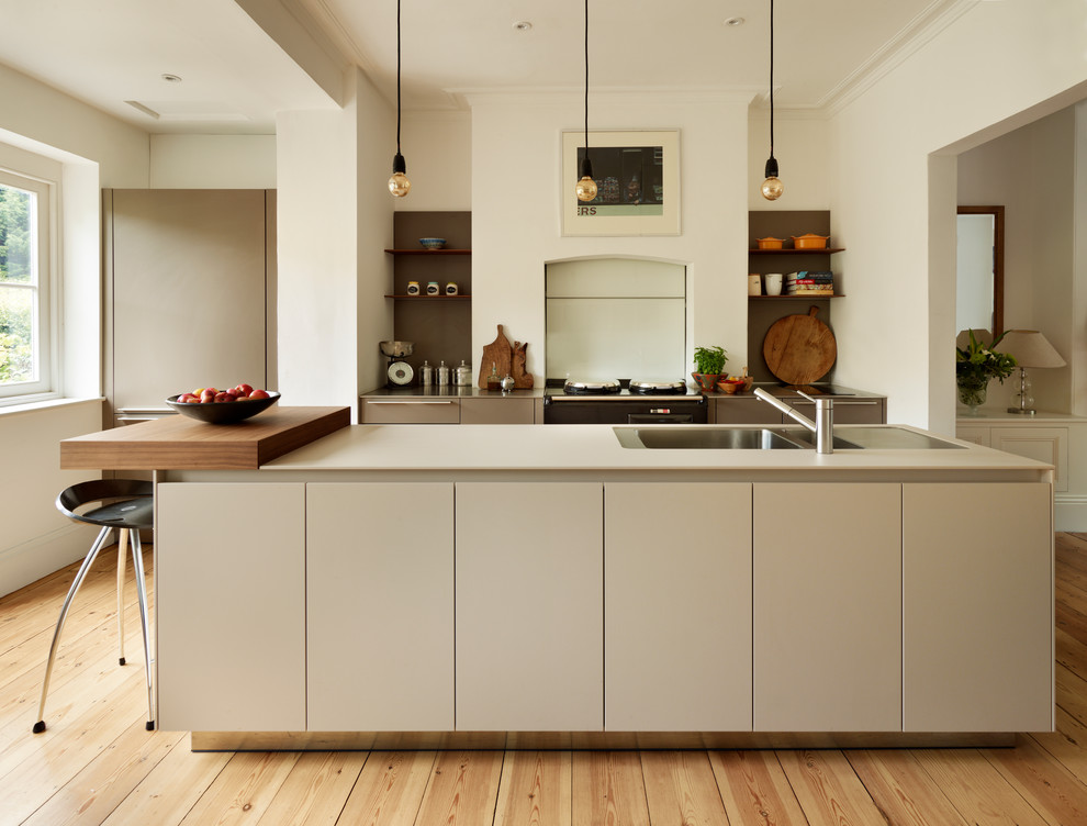 Inspiration for a contemporary kitchen in Oxfordshire with a double-bowl sink, flat-panel cabinets, white cabinets, light hardwood flooring and an island.