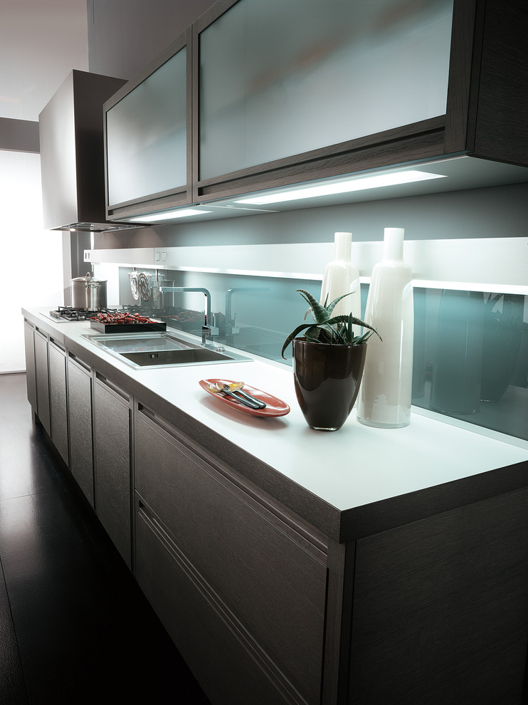 Immagine di una cucina design di medie dimensioni con lavello a doppia vasca, ante lisce, ante grigie, top in quarzo composito, paraspruzzi verde, paraspruzzi con lastra di vetro, elettrodomestici da incasso e pavimento in cemento
