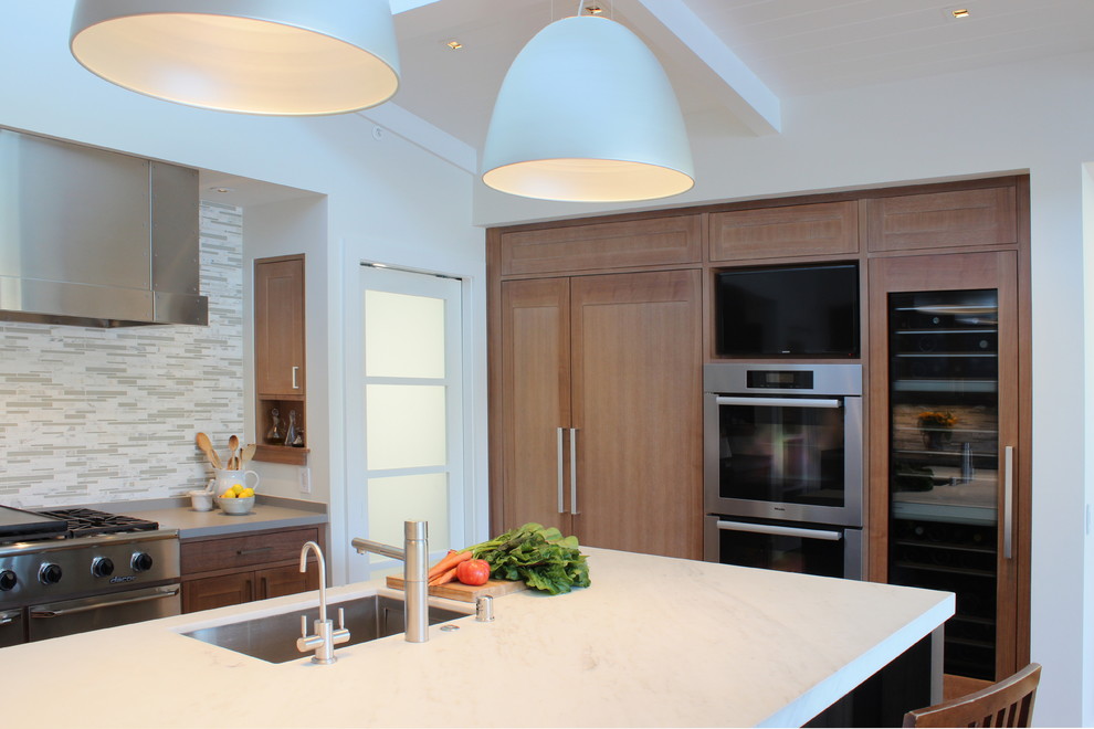 This is an example of an expansive classic kitchen/diner in San Francisco with a submerged sink, recessed-panel cabinets, light wood cabinets, stainless steel appliances, light hardwood flooring, marble worktops, grey splashback and an island.