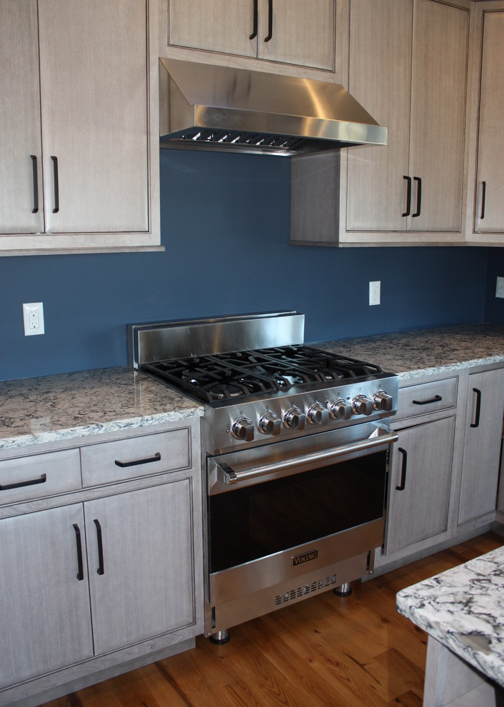 Foto di una cucina con lavello a doppia vasca, ante lisce, ante grigie, elettrodomestici in acciaio inossidabile, pavimento in legno massello medio e pavimento giallo