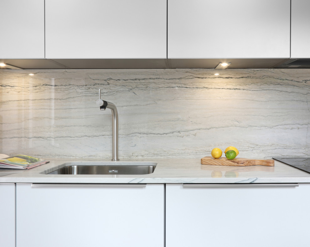 Inspiration for a small contemporary single-wall kitchen in Berkshire with an integrated sink, flat-panel cabinets, white cabinets, composite countertops, white splashback, stone slab splashback and white worktops.