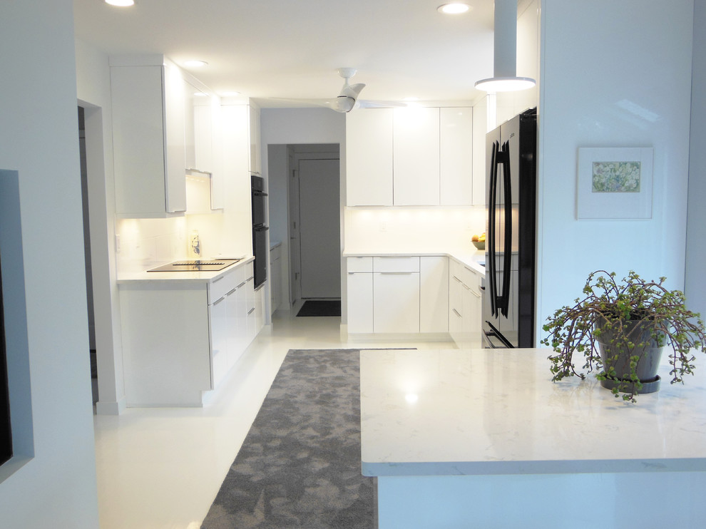 Exempel på ett mellanstort modernt u-kök, med en undermonterad diskho, släta luckor, vita skåp, bänkskiva i kvarts, vitt stänkskydd, svarta vitvaror, målat trägolv och en köksö