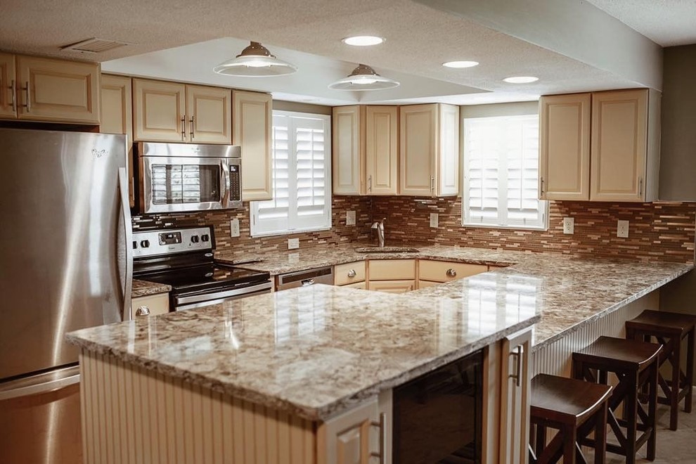 Example of a mid-sized trendy u-shaped beige floor kitchen design in Tampa with a single-bowl sink, raised-panel cabinets, beige cabinets, quartz countertops, brown backsplash, stainless steel appliances and a peninsula