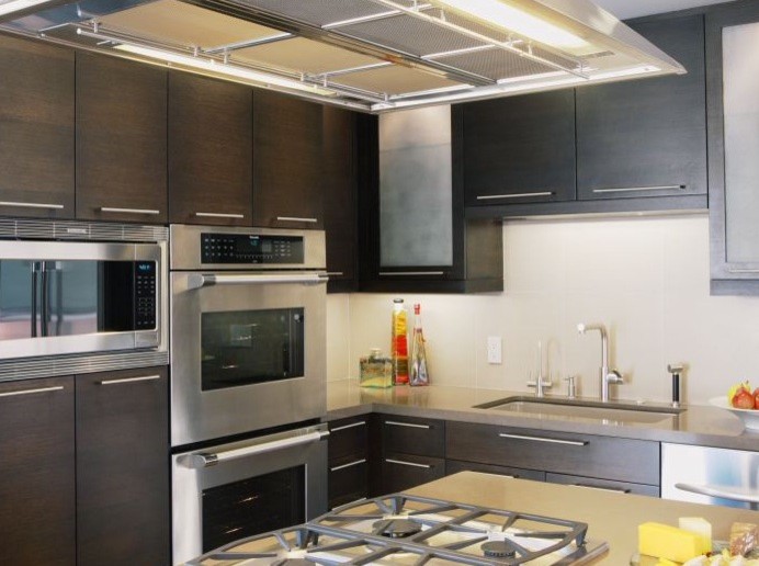 Foto di una cucina contemporanea di medie dimensioni con lavello sottopiano, ante lisce, ante in legno bruno, elettrodomestici in acciaio inossidabile e pavimento in legno massello medio
