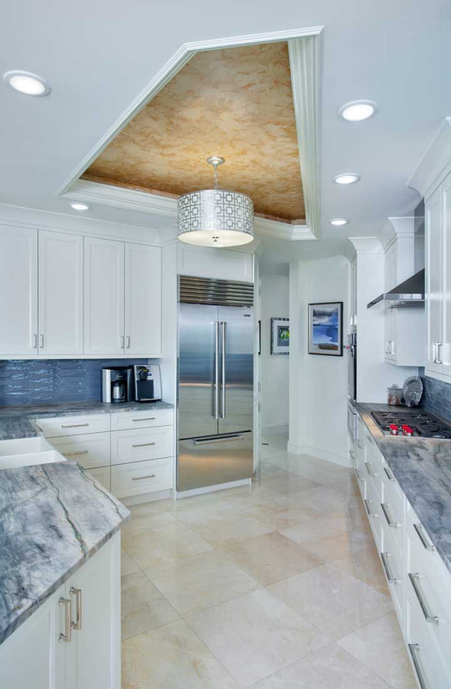 Photo of a medium sized contemporary galley kitchen/diner in Miami with recessed-panel cabinets, white cabinets, engineered stone countertops, blue splashback, porcelain splashback, stainless steel appliances, porcelain flooring, a breakfast bar, white floors, multicoloured worktops, a drop ceiling and a belfast sink.