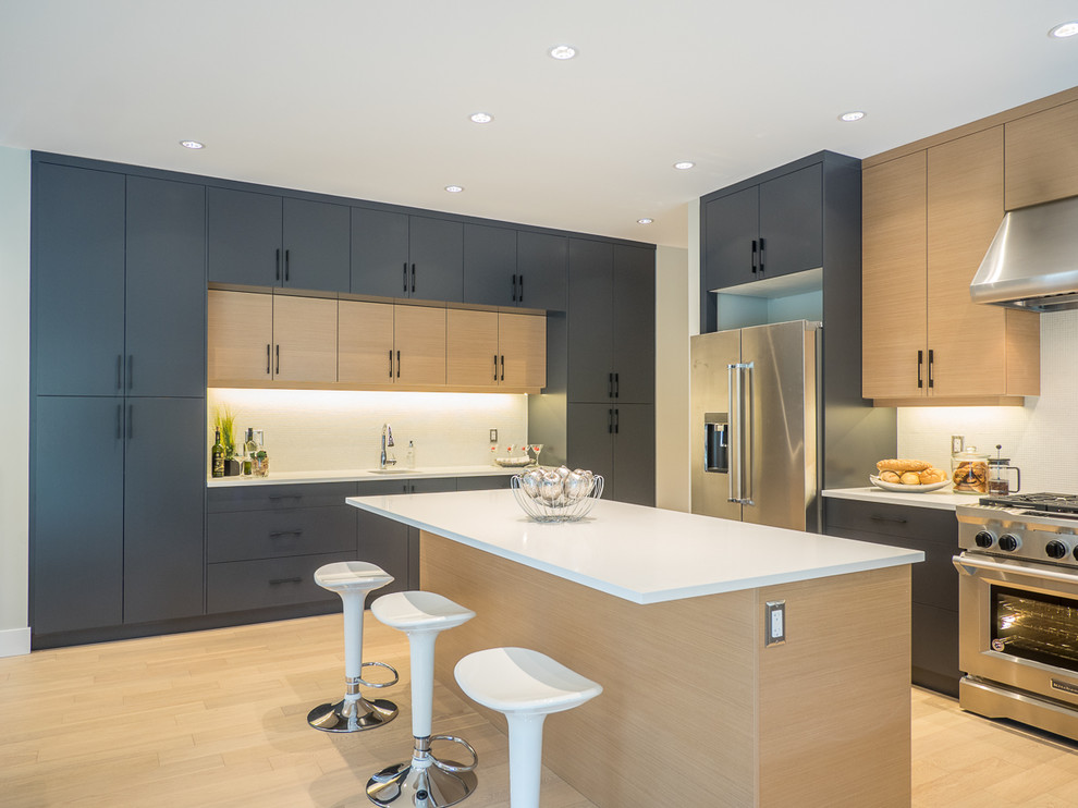 Moderne Wohnküche in L-Form mit Unterbauwaschbecken, flächenbündigen Schrankfronten, grauen Schränken, Küchenrückwand in Weiß, Küchengeräten aus Edelstahl, hellem Holzboden, Kücheninsel und beigem Boden in Vancouver