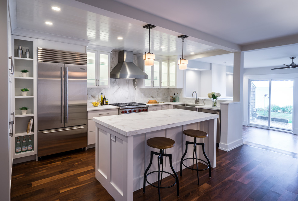 Example of a mid-sized transitional u-shaped dark wood floor kitchen pantry design in Burlington with a farmhouse sink, shaker cabinets, white cabinets, marble countertops, stone slab backsplash, stainless steel appliances and an island