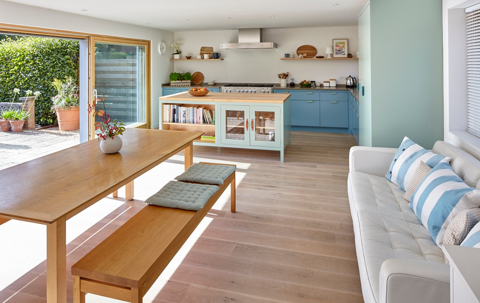 Große Moderne Wohnküche mit Kücheninsel, flächenbündigen Schrankfronten, Kalkstein-Arbeitsplatte, Küchengeräten aus Edelstahl, Unterbauwaschbecken und hellem Holzboden in Berkshire