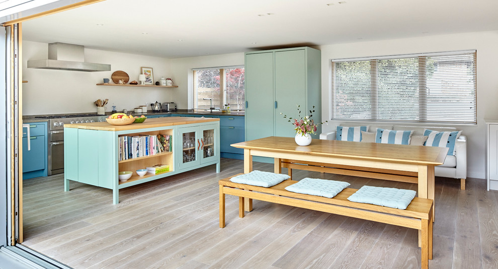 Modern inredning av ett stort kök och matrum, med en köksö, bänkskiva i kalksten, rostfria vitvaror, ljust trägolv, släta luckor och en undermonterad diskho