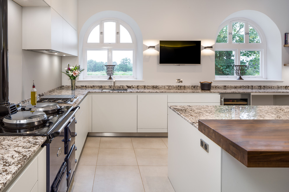 Inspiration for a medium sized contemporary u-shaped kitchen/diner in Devon with a built-in sink, flat-panel cabinets, white cabinets, granite worktops, coloured appliances, porcelain flooring, an island and grey floors.