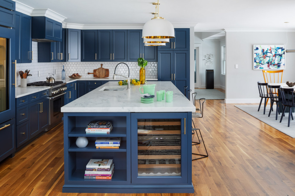 Kitchen - transitional l-shaped medium tone wood floor and brown floor kitchen idea in Boston with an undermount sink, recessed-panel cabinets, blue cabinets, white backsplash, mosaic tile backsplash, paneled appliances, an island and white countertops