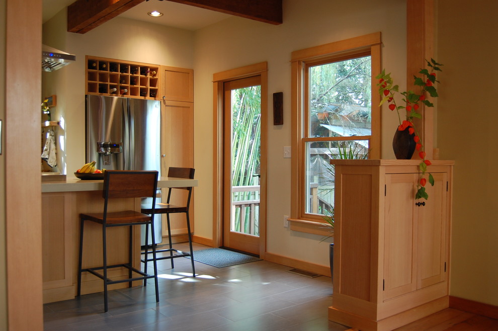 Example of an arts and crafts kitchen design in Portland with stainless steel appliances, shaker cabinets, light wood cabinets, quartz countertops and an island