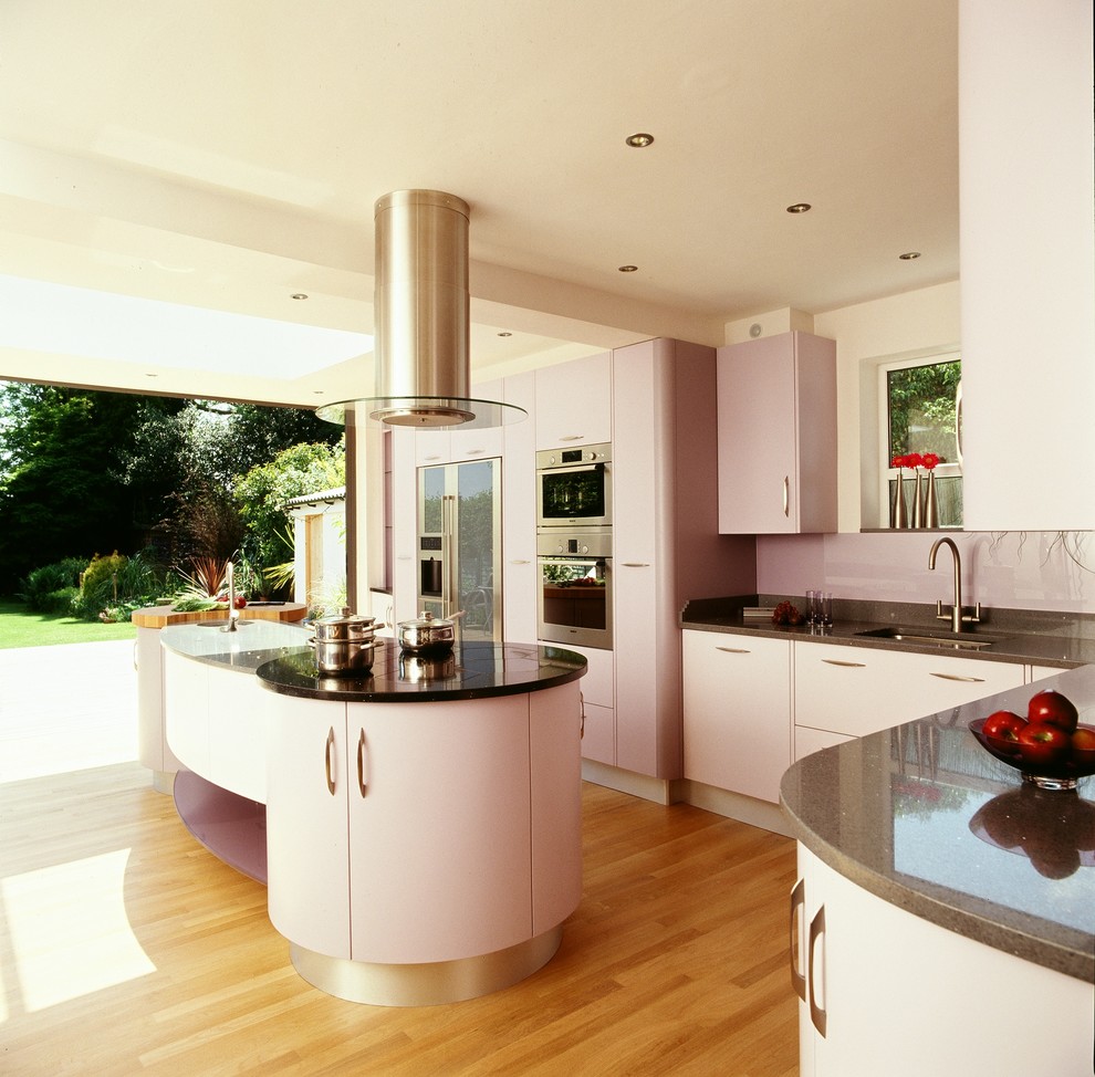 Inspiration for a large contemporary l-shaped open plan kitchen in Buckinghamshire with an integrated sink, flat-panel cabinets, quartz worktops, glass sheet splashback, light hardwood flooring and an island.