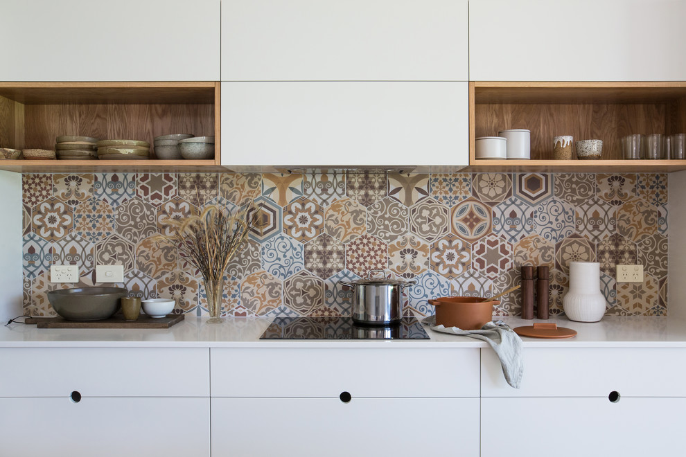 Design ideas for a large contemporary galley kitchen pantry in Other with a double-bowl sink, flat-panel cabinets, white cabinets, composite countertops, multi-coloured splashback, ceramic splashback, stainless steel appliances, light hardwood flooring, an island, brown floors and white worktops.