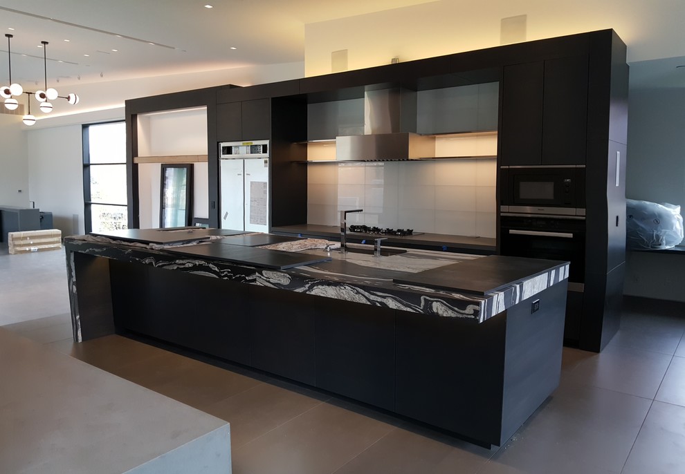 Inspiration for a large contemporary single-wall open plan kitchen in Denver with a submerged sink, flat-panel cabinets, dark wood cabinets, white splashback, glass tiled splashback, stainless steel appliances, an island and concrete flooring.