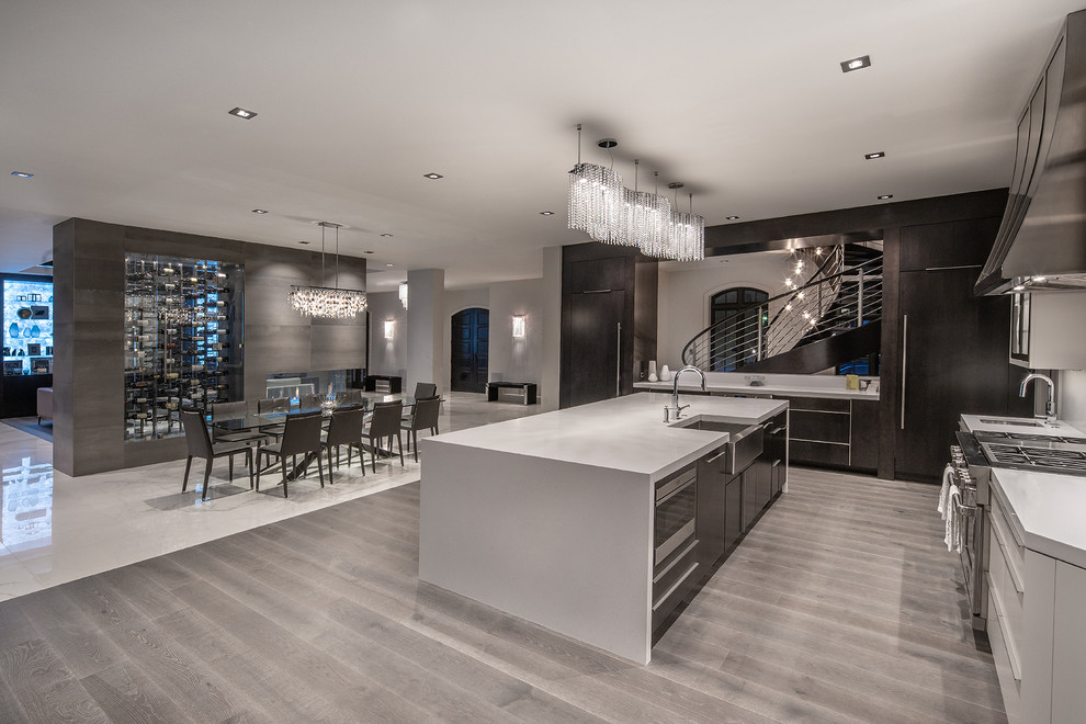 Inspiration for a contemporary l-shaped kitchen/diner in St Louis with a belfast sink, flat-panel cabinets, black cabinets, stainless steel appliances, light hardwood flooring, an island, grey floors and white worktops.