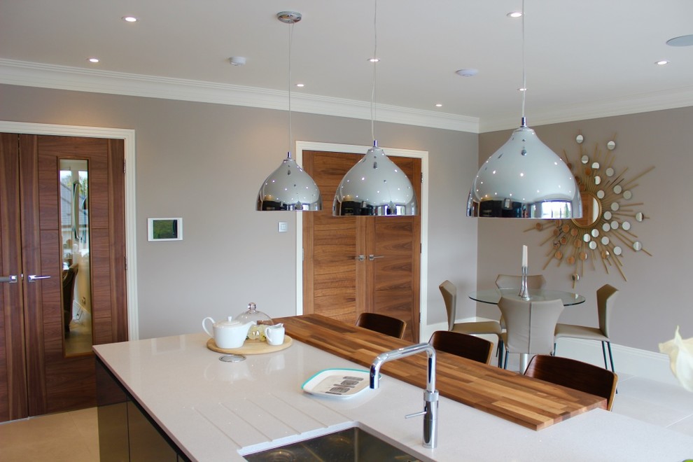 This is an example of a large modern single-wall kitchen/diner in Buckinghamshire with a built-in sink, flat-panel cabinets, grey cabinets, quartz worktops, red splashback, stainless steel appliances, porcelain flooring, an island and glass sheet splashback.