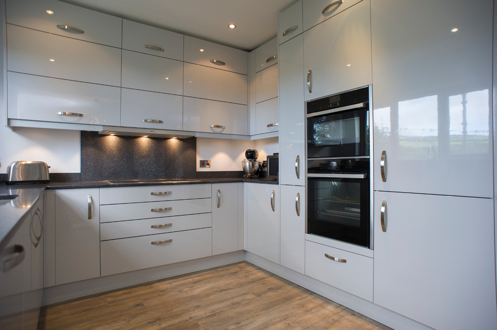 This is an example of a medium sized contemporary u-shaped kitchen/diner in Other with an integrated sink, flat-panel cabinets, grey cabinets, quartz worktops, grey splashback and integrated appliances.