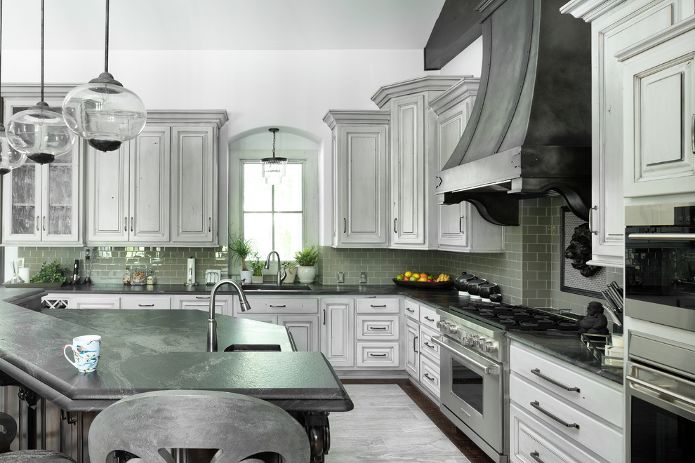 Modern inredning av ett stort kök, med en undermonterad diskho, luckor med upphöjd panel, grå skåp, granitbänkskiva, grått stänkskydd, stänkskydd i terrakottakakel, rostfria vitvaror och en köksö