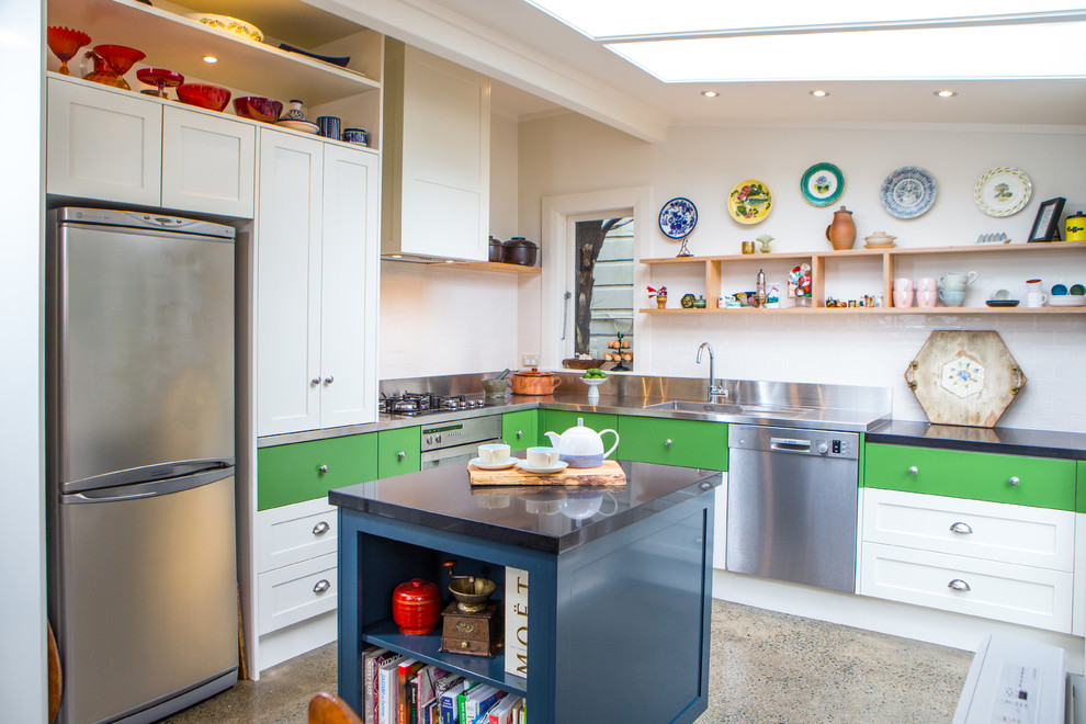 ウェリントンにある高級な小さなエクレクティックスタイルのおしゃれなキッチン (ダブルシンク、オープンシェルフ、ステンレスカウンター、白いキッチンパネル、セラミックタイルのキッチンパネル、シルバーの調理設備、コンクリートの床) の写真
