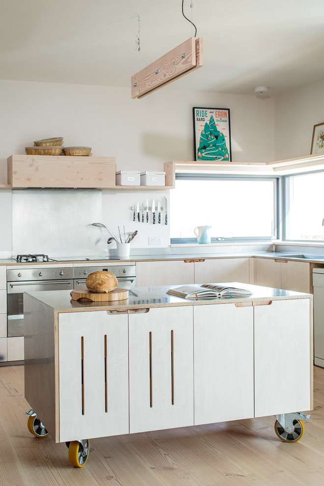 Design ideas for a medium sized scandinavian l-shaped kitchen in Other with flat-panel cabinets, light wood cabinets, stainless steel worktops, metallic splashback, stainless steel appliances, light hardwood flooring, an island and a belfast sink.