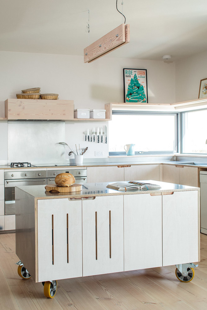 Inspiration for a mid-sized scandinavian l-shaped light wood floor kitchen remodel in Other with flat-panel cabinets, light wood cabinets, stainless steel countertops, metallic backsplash, stainless steel appliances, an island and a farmhouse sink