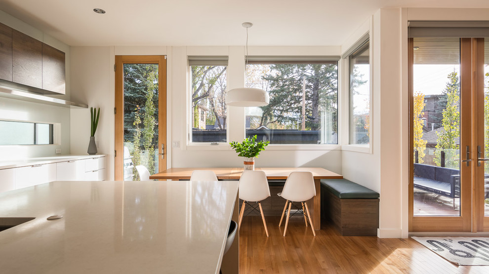 Cette image montre une cuisine américaine parallèle et encastrable design en bois foncé de taille moyenne avec un évier posé, un placard à porte plane, un sol en bois brun, îlot et un sol marron.