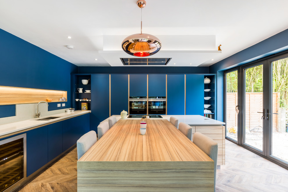 Immagine di una cucina ad ambiente unico contemporanea con ante lisce, ante blu, top in quarzite e top bianco