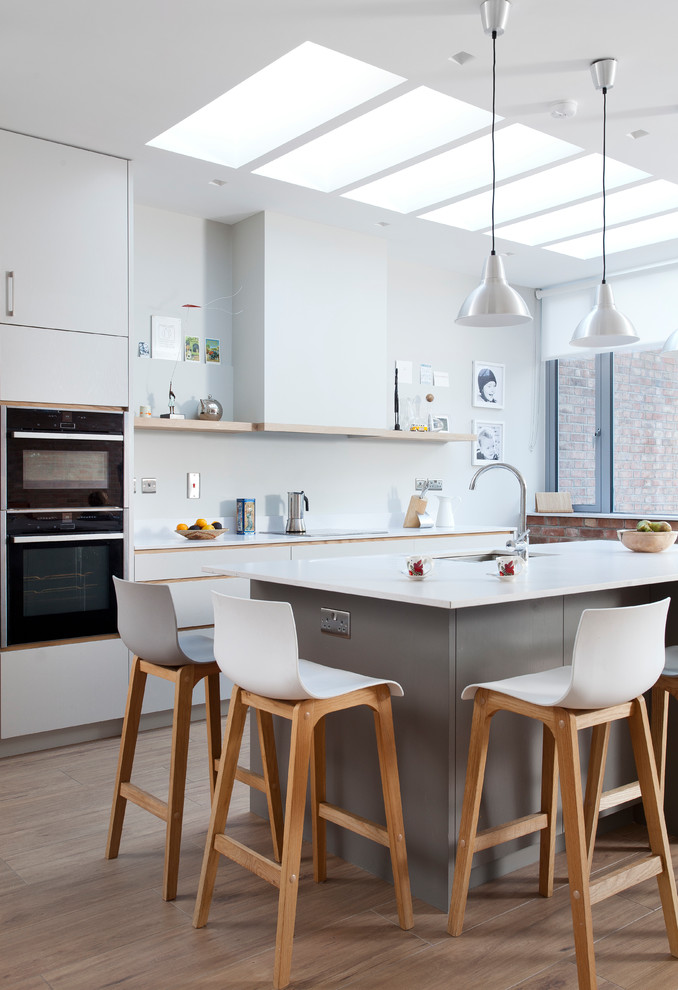 Источник вдохновения для домашнего уюта: кухня среднего размера в современном стиле с плоскими фасадами, полом из ламината и островом