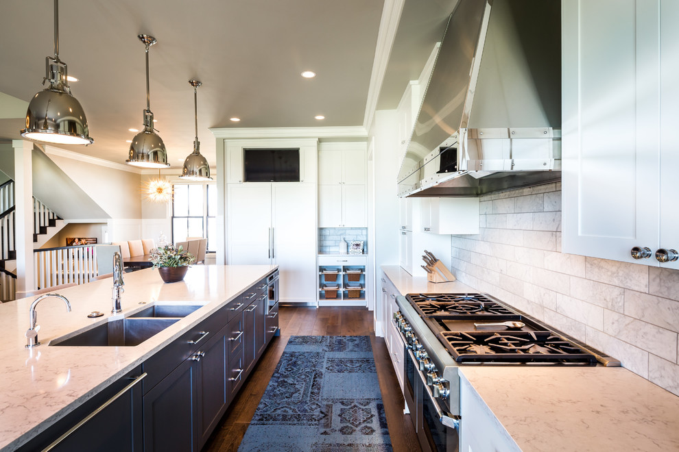 Exempel på ett lantligt grå grått kök, med en undermonterad diskho, skåp i shakerstil, vita skåp, grått stänkskydd, stänkskydd i tunnelbanekakel, integrerade vitvaror, mörkt trägolv, en köksö och brunt golv