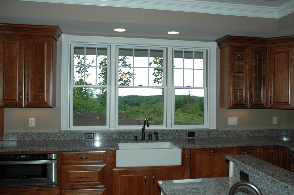 Foto de cocina campestre grande con fregadero sobremueble, armarios con paneles con relieve, puertas de armario de madera en tonos medios, encimera de granito y una isla