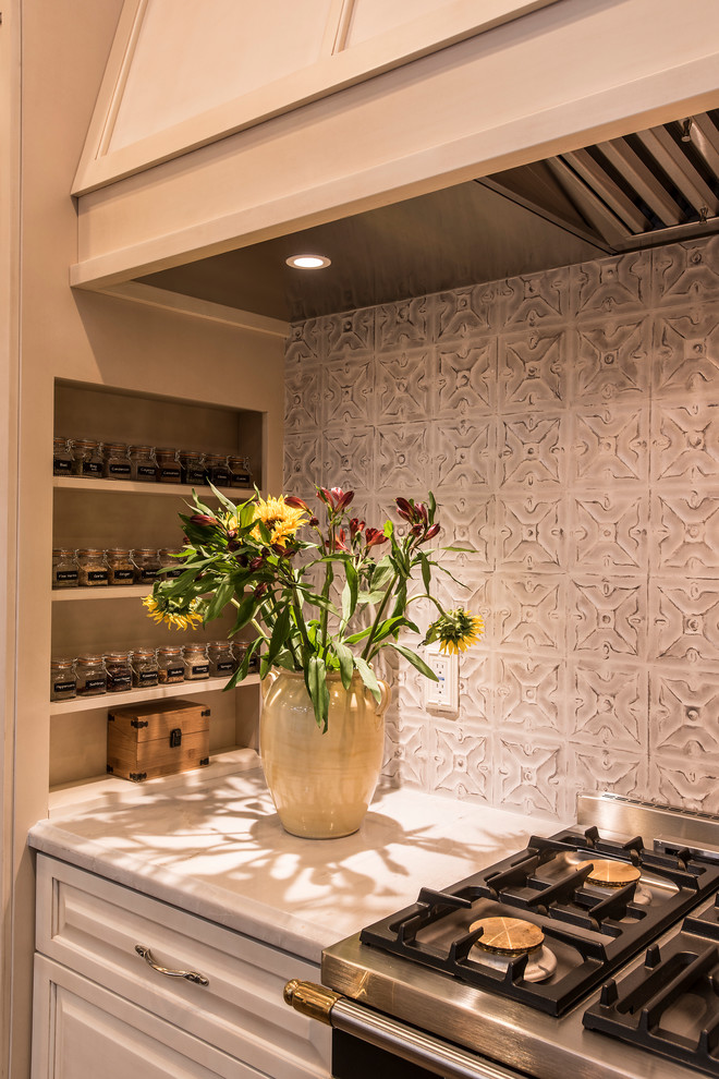 Inredning av ett lantligt stort vit vitt kök, med en rustik diskho, luckor med upphöjd panel, beige skåp, marmorbänkskiva, integrerade vitvaror, travertin golv, en köksö och brunt golv