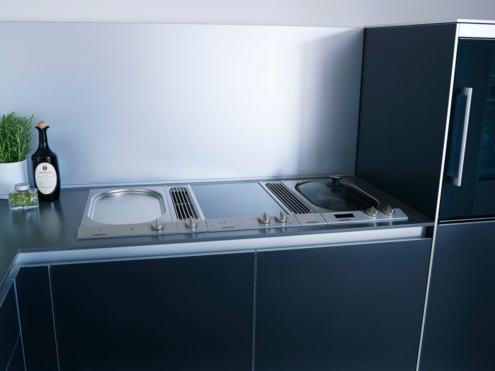 Esempio di una cucina minimalista di medie dimensioni con paraspruzzi a effetto metallico, ante lisce, ante nere, top in acciaio inossidabile e elettrodomestici neri