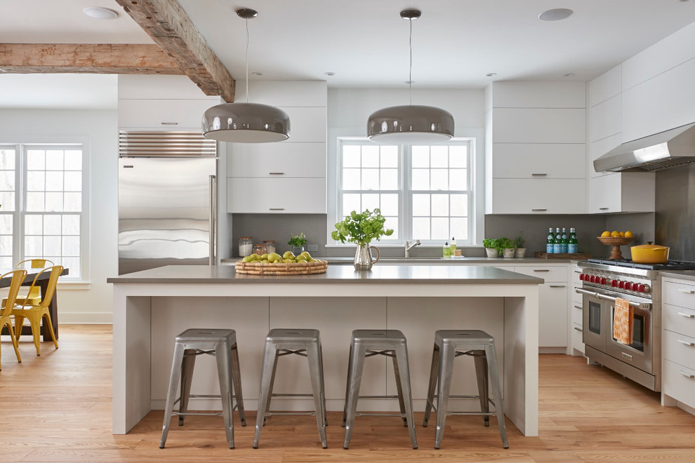 This is an example of a contemporary l-shaped kitchen/diner in Bridgeport with flat-panel cabinets, white cabinets, grey splashback, stainless steel appliances, light hardwood flooring and an island.