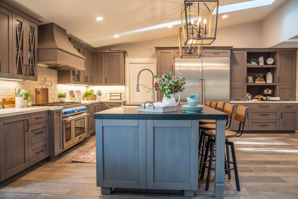 Country l-shaped dark wood floor, brown floor and vaulted ceiling kitchen photo in San Diego with a farmhouse sink, shaker cabinets, medium tone wood cabinets, gray backsplash, stainless steel appliances, an island and white countertops