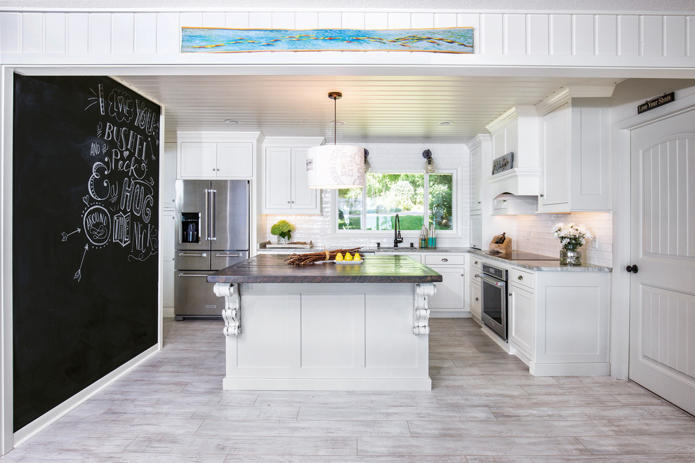 Exempel på ett lantligt l-kök, med en undermonterad diskho, skåp i shakerstil, vita skåp, vitt stänkskydd, stänkskydd i tunnelbanekakel, rostfria vitvaror och en köksö