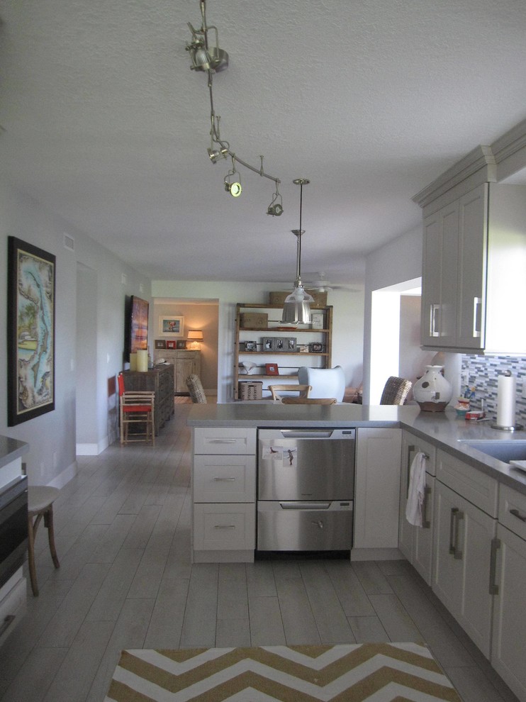Inredning av ett klassiskt avskilt, mellanstort linjärt kök, med en undermonterad diskho, luckor med infälld panel, vita skåp, bänkskiva i kvarts, flerfärgad stänkskydd, stänkskydd i stickkakel, rostfria vitvaror, klinkergolv i porslin och grått golv