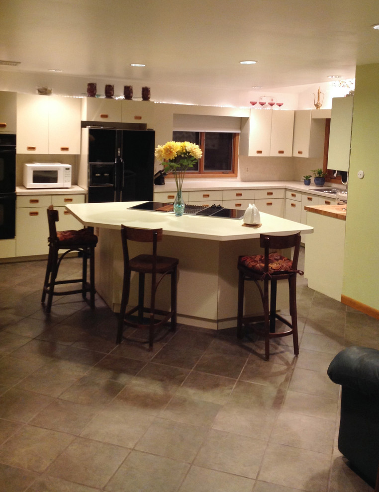 Example of a minimalist u-shaped ceramic tile eat-in kitchen design in New York with flat-panel cabinets, beige cabinets, laminate countertops, beige backsplash, black appliances and an island