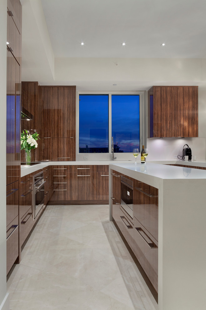 Photo of a contemporary u-shaped kitchen in Miami with flat-panel cabinets, medium wood cabinets, an island, engineered stone countertops, grey splashback and integrated appliances.