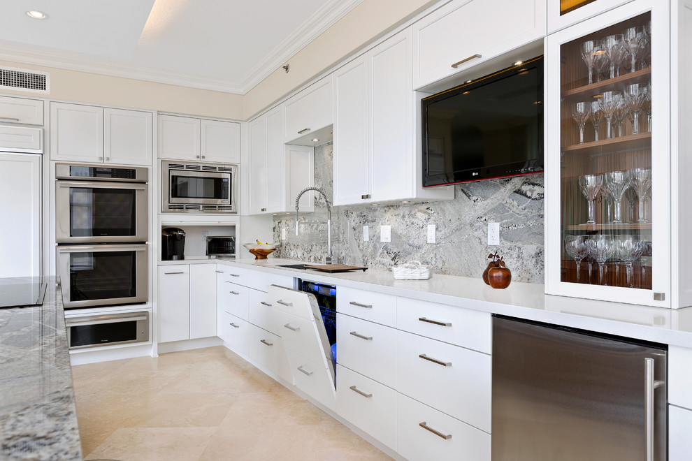 Ejemplo de cocinas en L contemporánea con una isla, armarios estilo shaker, puertas de armario blancas, encimera de cuarzo compacto, electrodomésticos con paneles y suelo de travertino