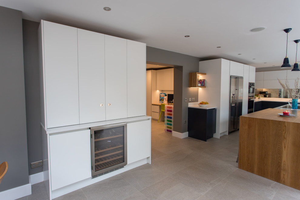 Inspiration for an expansive contemporary l-shaped kitchen/diner in Hertfordshire with a built-in sink, flat-panel cabinets, blue cabinets, quartz worktops, metallic splashback, mirror splashback, stainless steel appliances, porcelain flooring, an island, white floors and white worktops.