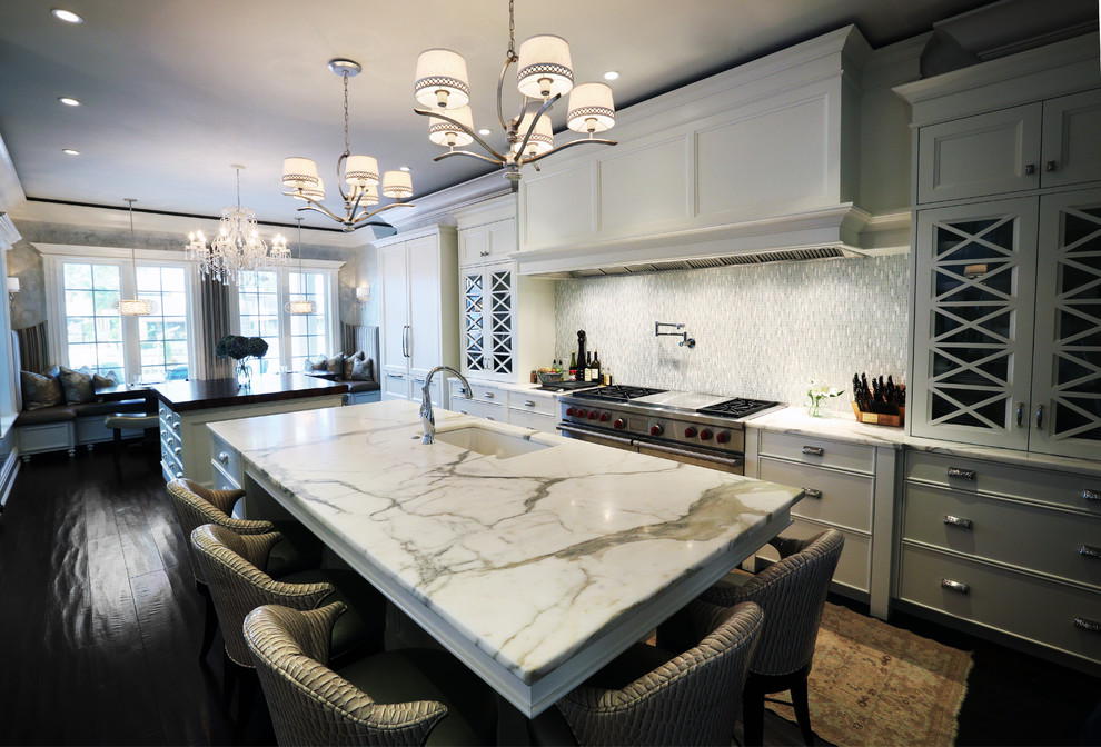 Inspiration for a large contemporary u-shaped dark wood floor eat-in kitchen remodel in Tampa with an undermount sink, white cabinets, marble countertops, white backsplash, glass tile backsplash, stainless steel appliances, beaded inset cabinets and an island