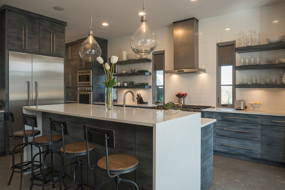 Example of a large trendy single-wall concrete floor eat-in kitchen design in Dallas with a single-bowl sink, shaker cabinets, gray cabinets, granite countertops, white backsplash, ceramic backsplash, stainless steel appliances and an island