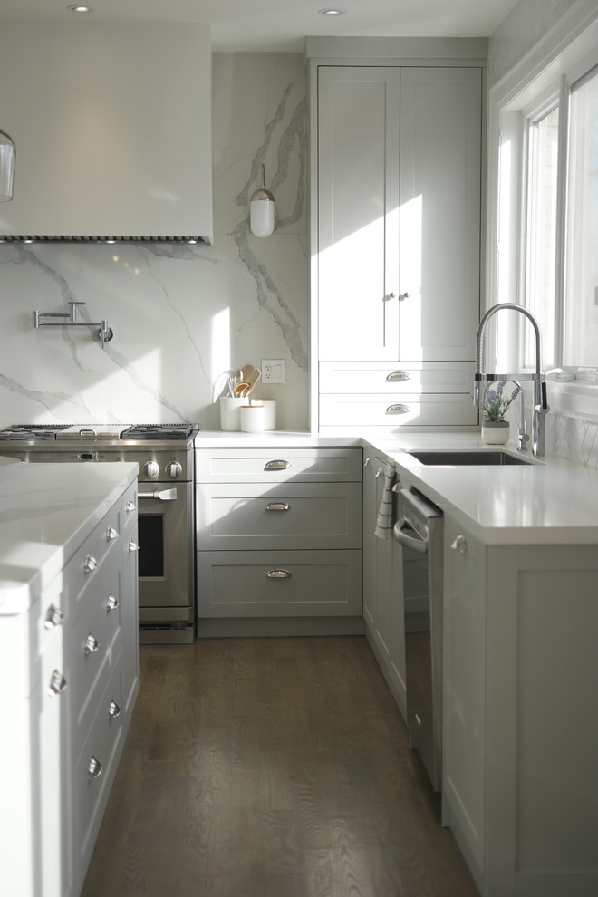 Example of a large trendy u-shaped light wood floor and gray floor eat-in kitchen design in Toronto with a single-bowl sink, shaker cabinets, gray cabinets, quartz countertops, white backsplash, stone slab backsplash, stainless steel appliances and an island