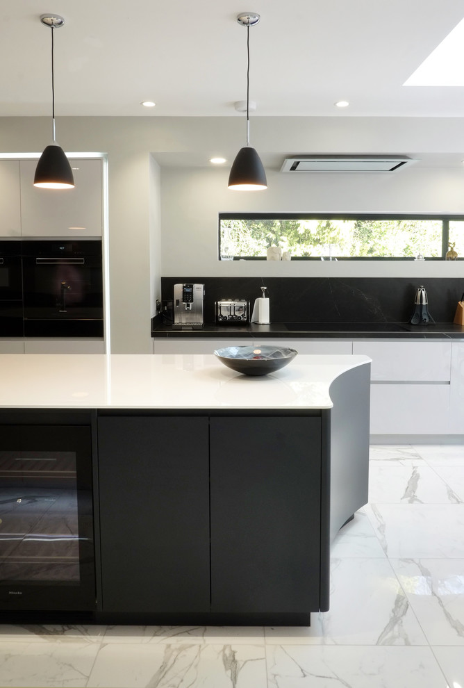 This is an example of a contemporary open plan kitchen in Other with a submerged sink, flat-panel cabinets, white cabinets, quartz worktops, black splashback, porcelain splashback, black appliances, porcelain flooring, an island, white floors and white worktops.