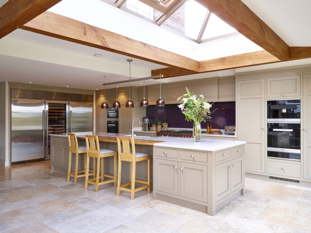 Inspiration for a large classic l-shaped kitchen/diner in Other with a belfast sink, beaded cabinets, grey cabinets, glass sheet splashback, stainless steel appliances, an island, white worktops and grey floors.