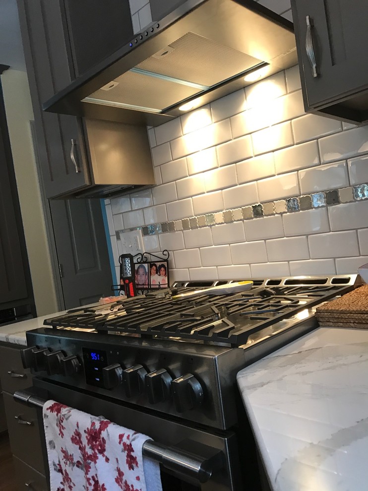 ニューヨークにある中くらいなトランジショナルスタイルのおしゃれなキッチン (シングルシンク、シェーカースタイル扉のキャビネット、グレーのキャビネット、大理石カウンター、白いキッチンパネル、サブウェイタイルのキッチンパネル、シルバーの調理設備、無垢フローリング) の写真