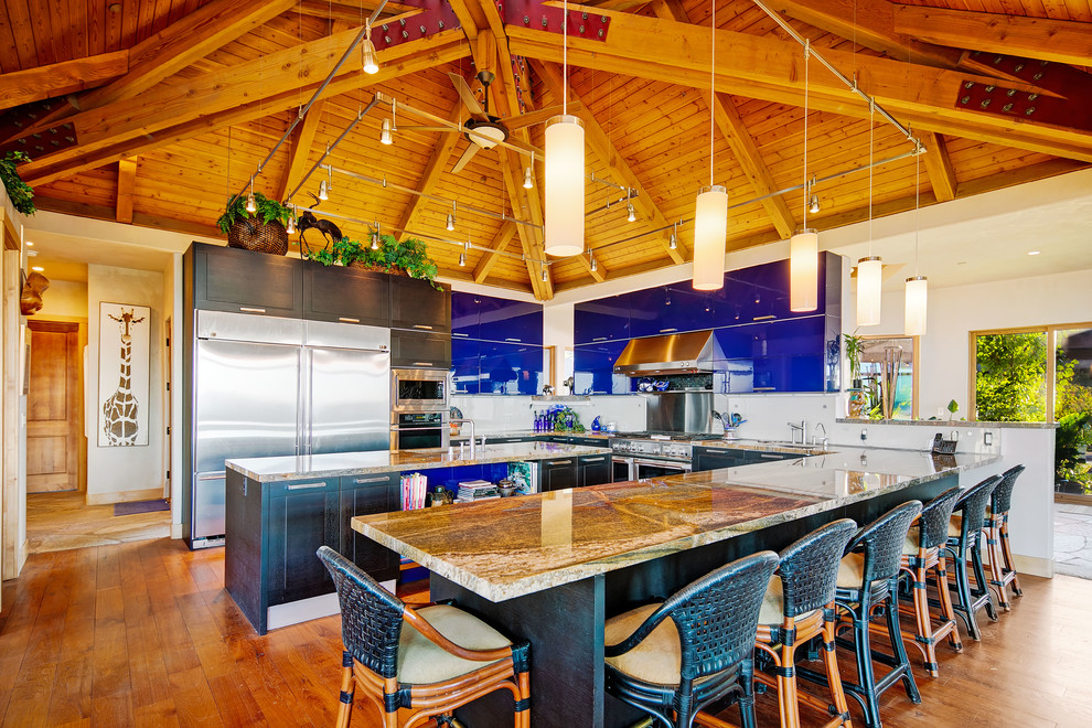 Foto på ett funkis flerfärgad u-kök, med en undermonterad diskho, släta luckor, blå skåp, stänkskydd med metallisk yta, rostfria vitvaror, mellanmörkt trägolv, en köksö och orange golv
