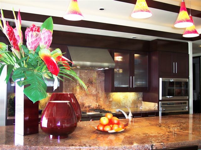 Einzeilige, Geräumige Moderne Wohnküche mit Unterbauwaschbecken, Glasfronten, braunen Schränken, Granit-Arbeitsplatte, Küchenrückwand in Rot, Rückwand aus Stein, Küchengeräten aus Edelstahl, Korkboden, zwei Kücheninseln und braunem Boden in Hawaii