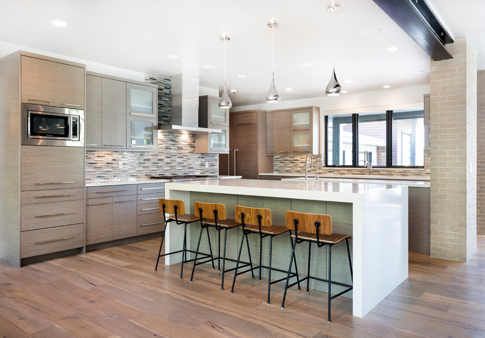 Photo of a contemporary l-shaped kitchen in Salt Lake City with flat-panel cabinets, grey cabinets, multi-coloured splashback, matchstick tiled splashback, integrated appliances, medium hardwood flooring, brown floors, white worktops and multiple islands.